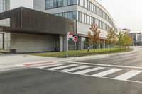 an intersection with a bus stop and an office building in the background at a corner