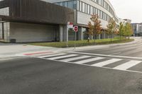 an intersection with a bus stop and an office building in the background at a corner