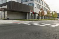 an intersection with a bus stop and an office building in the background at a corner