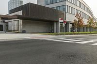 an intersection with a bus stop and an office building in the background at a corner