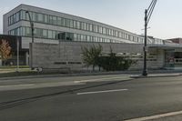 a grey colored building is situated on the corner of a street with a street light in the foreground, on a clear day