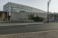 a grey colored building is situated on the corner of a street with a street light in the foreground, on a clear day