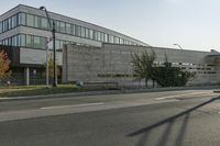 a grey colored building is situated on the corner of a street with a street light in the foreground, on a clear day