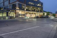 this is a city street corner with cars passing in front of it at night time