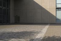 a man rides his skateboard on a city sidewalk near a building under an open sky