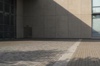 a man rides his skateboard on a city sidewalk near a building under an open sky