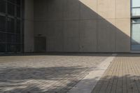 a man rides his skateboard on a city sidewalk near a building under an open sky