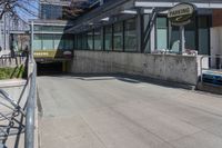 the entrance to a parking garage next to two empty benches and a building that says, no parking