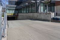 the entrance to a parking garage next to two empty benches and a building that says, no parking