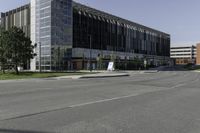 a large modern office building on a city street with trees outside the windows and grass on the other side