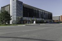 a large modern office building on a city street with trees outside the windows and grass on the other side