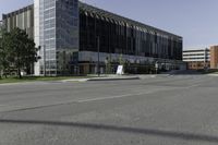 a large modern office building on a city street with trees outside the windows and grass on the other side