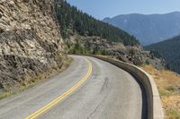 the view from an angle of a road near a mountain range is pictured on a clear day