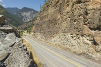 a narrow, curvy mountain road is surrounded by large rocks on either side of the road