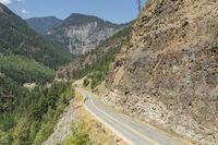 a narrow, curvy mountain road is surrounded by large rocks on either side of the road