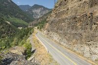 a narrow, curvy mountain road is surrounded by large rocks on either side of the road