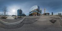 the reflection of a building on a fish eye lens is visible in this view of a curved, empty street