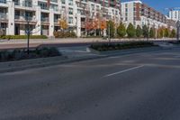 an empty street is lined with residential buildings, trees and shrubs in the middle of the photo