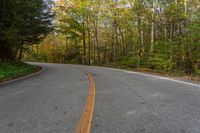 an empty road winding through woods in the fall leaves are changing colors while traffic signs line it