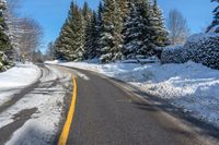 snowy mountain with snow - lined road and evergreen trees in backgound and blue sky