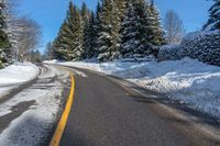 snowy mountain with snow - lined road and evergreen trees in backgound and blue sky