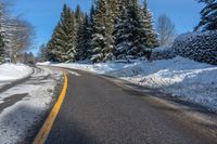 snowy mountain with snow - lined road and evergreen trees in backgound and blue sky