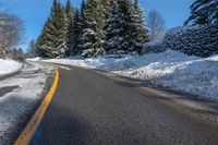 snowy mountain with snow - lined road and evergreen trees in backgound and blue sky