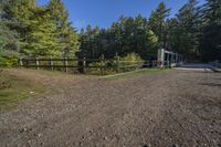 a trail leading up to an enclosed area in the woods of trees with a wooden fence