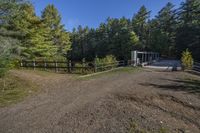 a trail leading up to an enclosed area in the woods of trees with a wooden fence