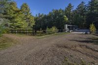 a trail leading up to an enclosed area in the woods of trees with a wooden fence