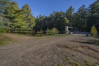 a trail leading up to an enclosed area in the woods of trees with a wooden fence