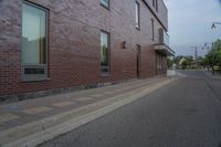 a side walk in front of a red brick building with a black door and windows