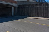 an asphalt street with yellow arrows painted on it's surface near an empty parking garage