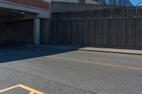 an asphalt street with yellow arrows painted on it's surface near an empty parking garage