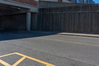 an asphalt street with yellow arrows painted on it's surface near an empty parking garage