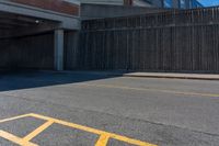 an asphalt street with yellow arrows painted on it's surface near an empty parking garage