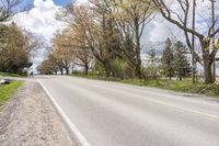 a person riding a bicycle on the street next to trees and grass with blue sky in background