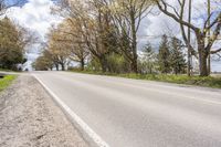 a person riding a bicycle on the street next to trees and grass with blue sky in background