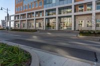 an empty street in front of some modern buildings in a city area of the sun