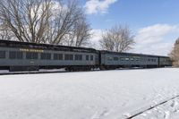 a train that is sitting in the snow on tracks in a field with snow covered ground