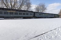 a train that is sitting in the snow on tracks in a field with snow covered ground