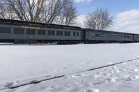 a train that is sitting in the snow on tracks in a field with snow covered ground