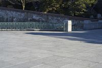 a skateboarder rides down the concrete path at a skate park while others watch