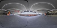 the skateboarder is riding down a ramp by itself in an underground facility or parking garage