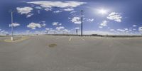 a parking lot with blue skies and clouds in the sky and poles with lights on top of it