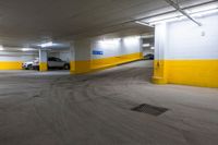 the empty parking area in a yellow and white building with some cars in it on the road