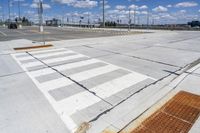 empty parking lot with a crosswalk and blue sky in the background with clouds on top