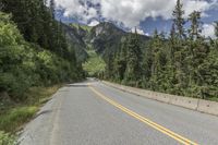 a mountain road is shown with trees in the background with mountains in the distance below