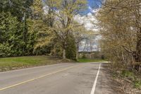 empty street with no cars in the distance near the wooded landscape on a sunny day