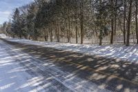 a snow covered street with a snowy fence in the distance and snow covered road leading the street